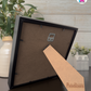 Crafted Memoirs Photo Frame By Printhaws Creations, Back View Of Matte Black Frame Showing MDF Backing With Foldable Easel And Sawtooth Hanger